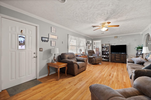 living room with ceiling fan, a textured ceiling, wood-type flooring, and ornamental molding