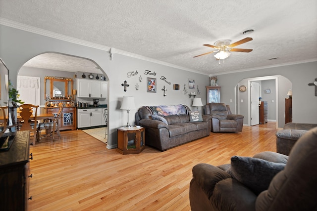 living room featuring ornamental molding, a textured ceiling, light hardwood / wood-style floors, and ceiling fan