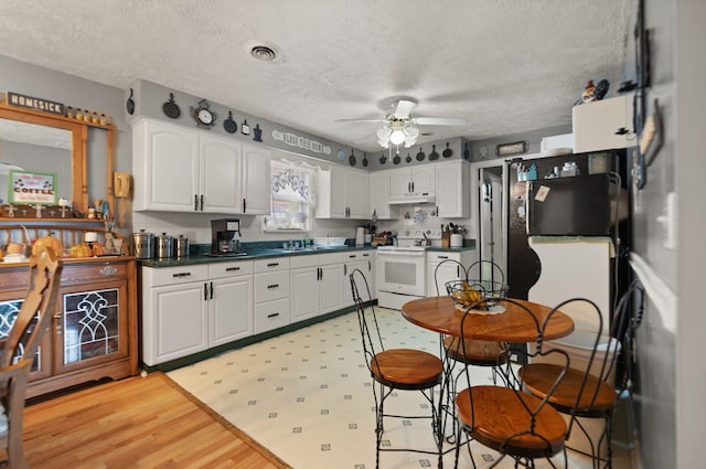 kitchen featuring a textured ceiling, ceiling fan, white range with electric stovetop, white cabinets, and light hardwood / wood-style flooring