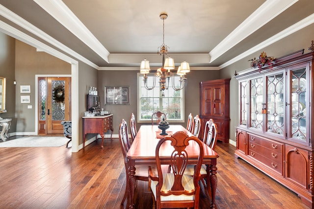 dining area featuring dark hardwood / wood-style flooring, a tray ceiling, a notable chandelier, and crown molding