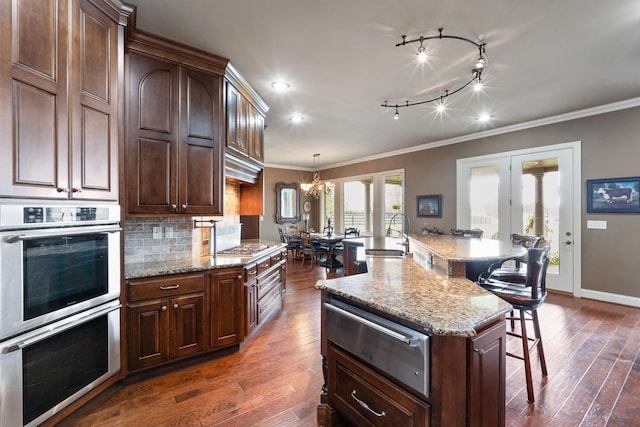 kitchen featuring a breakfast bar, an inviting chandelier, a spacious island, double oven, and dark wood-type flooring