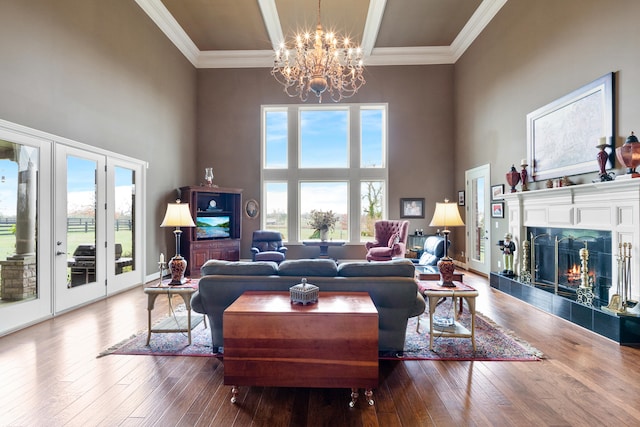 living room with crown molding, a tiled fireplace, wood-type flooring, and a high ceiling