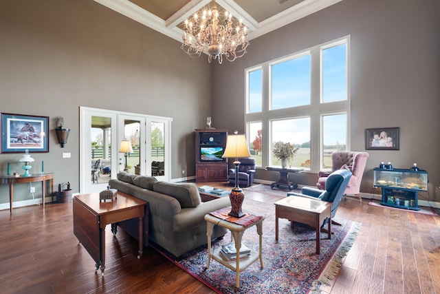 living room with ornamental molding, hardwood / wood-style floors, a healthy amount of sunlight, and a towering ceiling