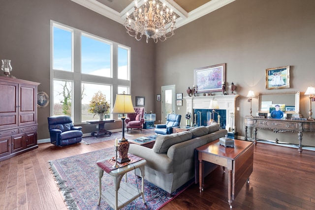 living room with hardwood / wood-style flooring, a towering ceiling, an inviting chandelier, and ornamental molding