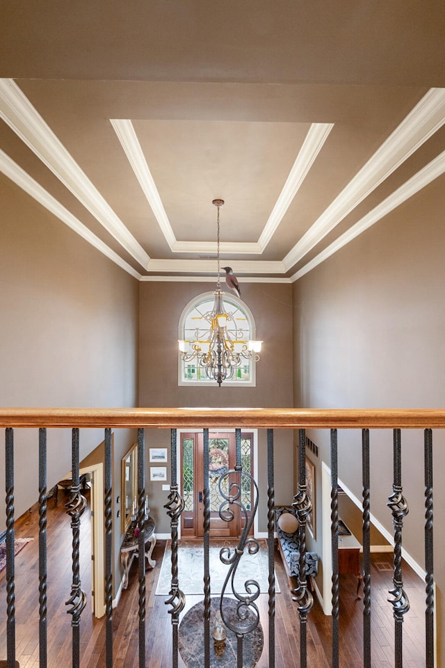 hallway featuring dark wood-type flooring, an inviting chandelier, crown molding, and a raised ceiling