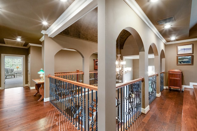 corridor featuring ornamental molding, wood-type flooring, and a notable chandelier