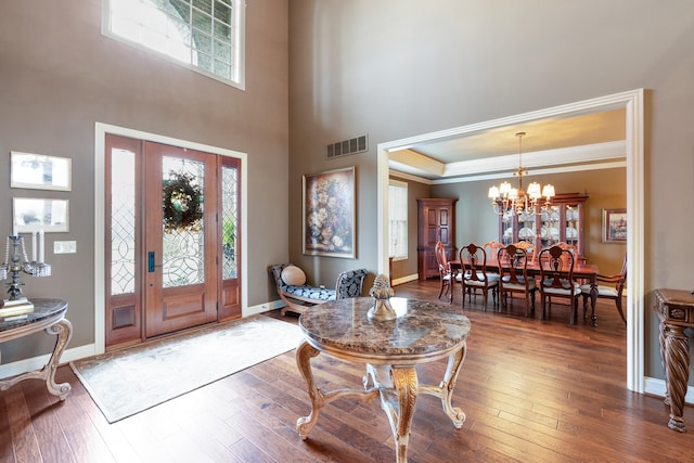 foyer entrance featuring dark hardwood / wood-style floors, a high ceiling, a tray ceiling, and an inviting chandelier