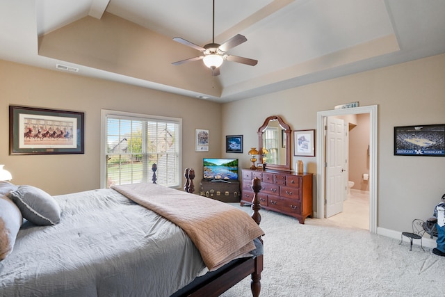 carpeted bedroom featuring ceiling fan, a tray ceiling, and connected bathroom