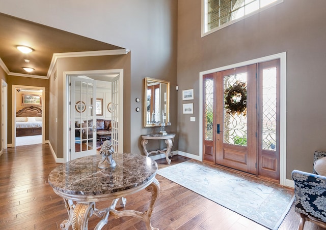 entrance foyer featuring a towering ceiling, wood-type flooring, and crown molding