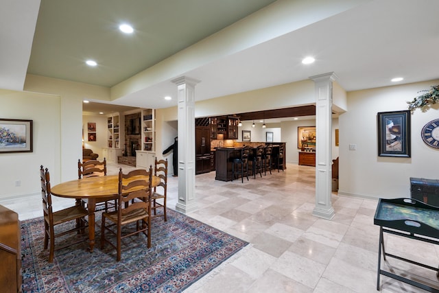 dining area with bar area, built in shelves, and decorative columns