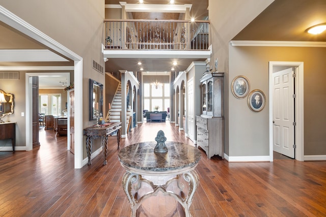 foyer featuring a towering ceiling, dark hardwood / wood-style floors, and crown molding