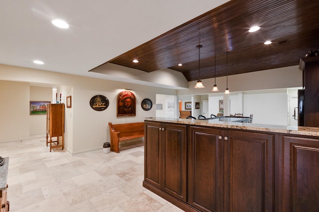 kitchen featuring light stone countertops, dark brown cabinets, pendant lighting, and black refrigerator