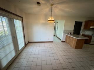 kitchen featuring white range oven, extractor fan, hanging light fixtures, and kitchen peninsula