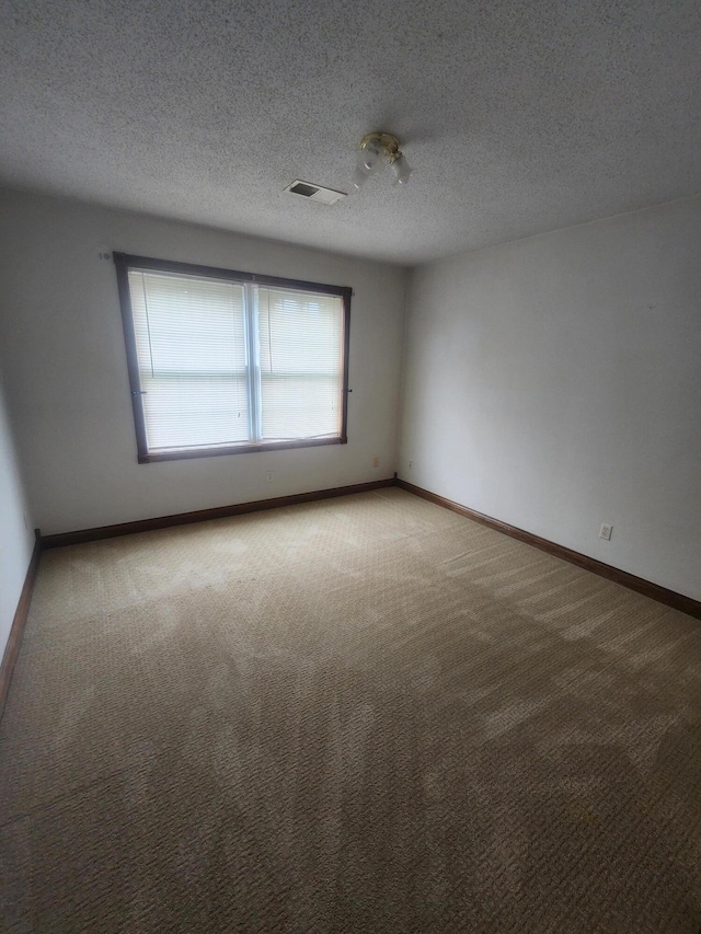 empty room featuring carpet and a textured ceiling