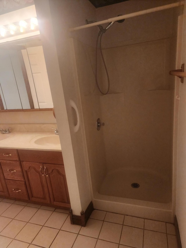 bathroom with tile patterned floors, a tile shower, and vanity