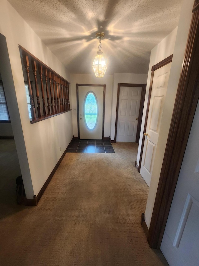 doorway to outside with dark carpet and a textured ceiling