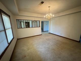 carpeted spare room with a chandelier