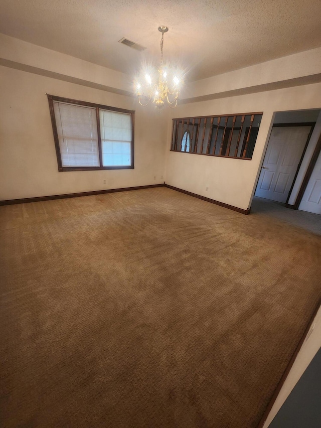 carpeted empty room featuring a notable chandelier and a textured ceiling