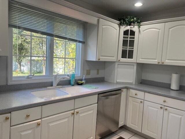 kitchen featuring dishwasher, light countertops, a sink, and white cabinets