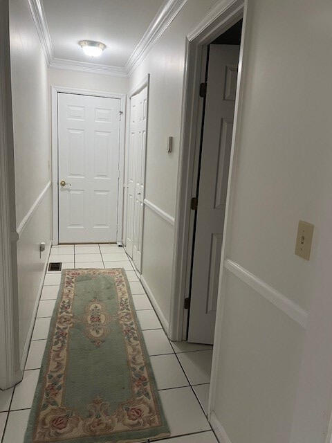 corridor with light tile patterned flooring and crown molding