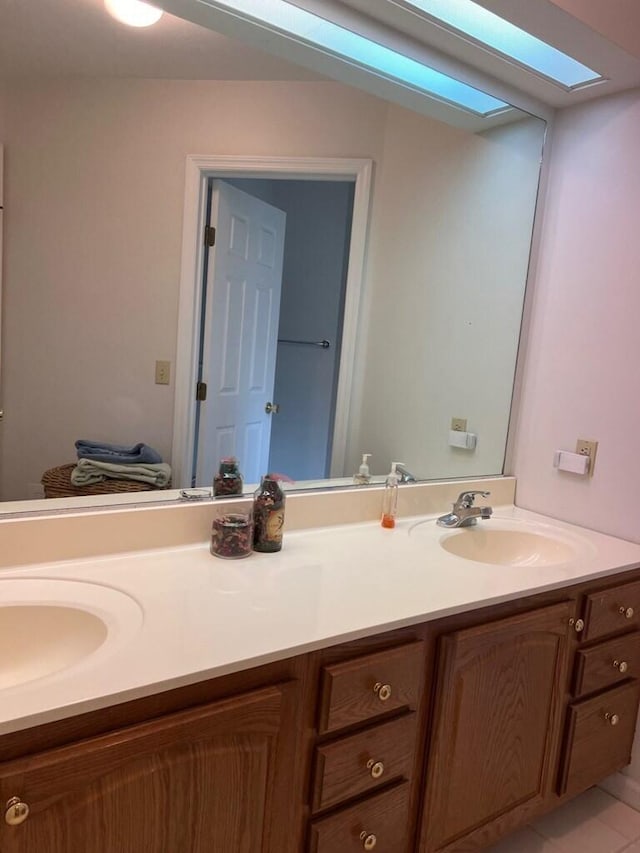 full bathroom featuring a skylight, tile patterned flooring, a sink, and double vanity