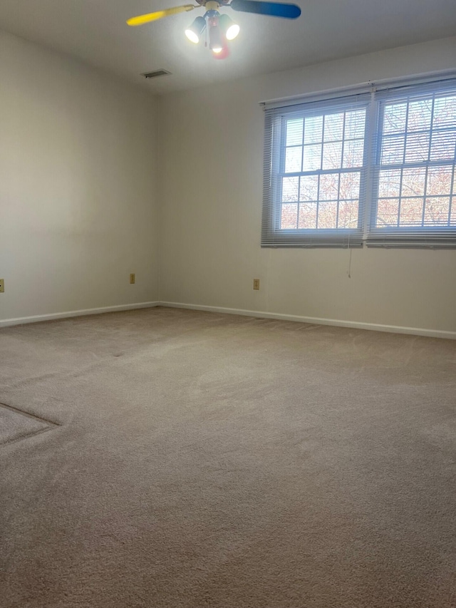 unfurnished room with a ceiling fan, carpet, visible vents, and baseboards