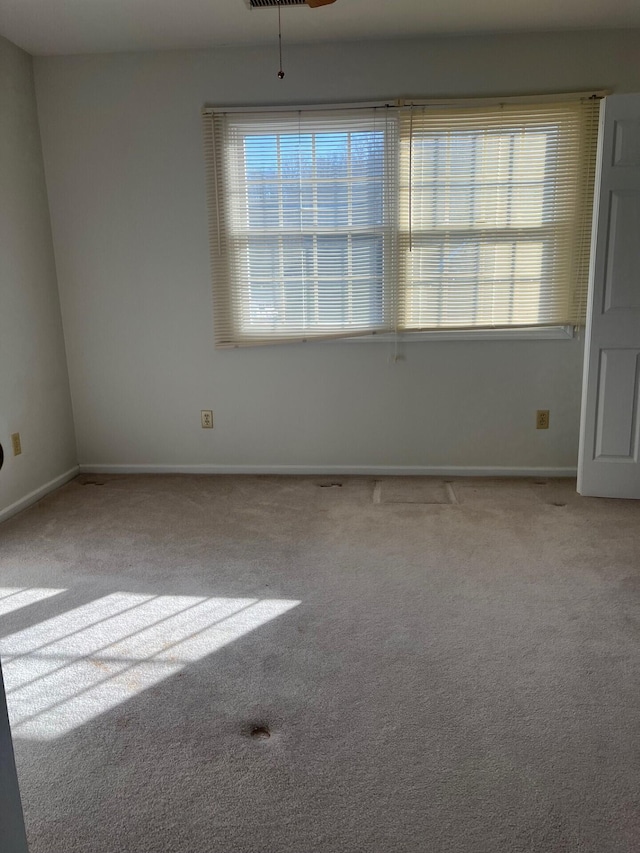 empty room with carpet floors, plenty of natural light, and baseboards