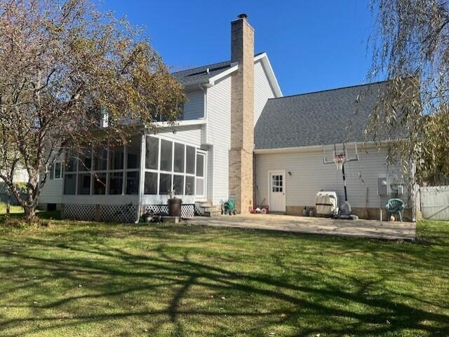 back of property featuring a sunroom, a chimney, and a yard