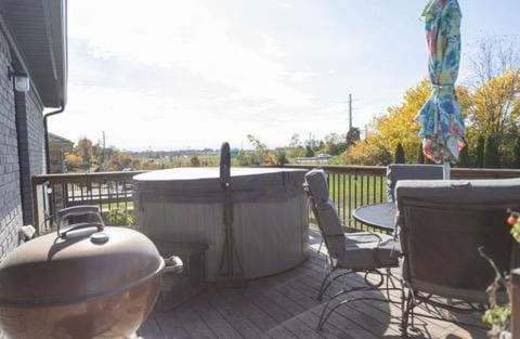 wooden terrace featuring a hot tub and a grill