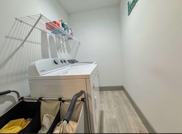 laundry area with light hardwood / wood-style flooring and washer and dryer