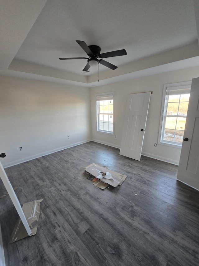 spare room featuring ceiling fan, a tray ceiling, and dark hardwood / wood-style flooring