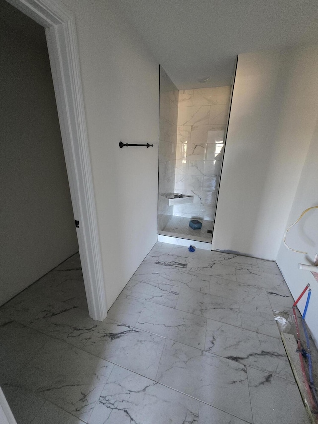 bathroom featuring a textured ceiling and tiled shower