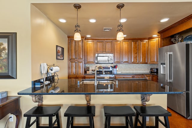 kitchen featuring decorative light fixtures, a breakfast bar, appliances with stainless steel finishes, and tasteful backsplash