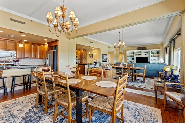 dining space featuring crown molding, dark hardwood / wood-style flooring, a chandelier, and sink