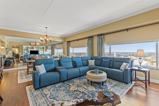 living room featuring crown molding, plenty of natural light, wood-type flooring, and a notable chandelier