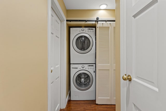 clothes washing area featuring dark wood-type flooring and stacked washer and clothes dryer