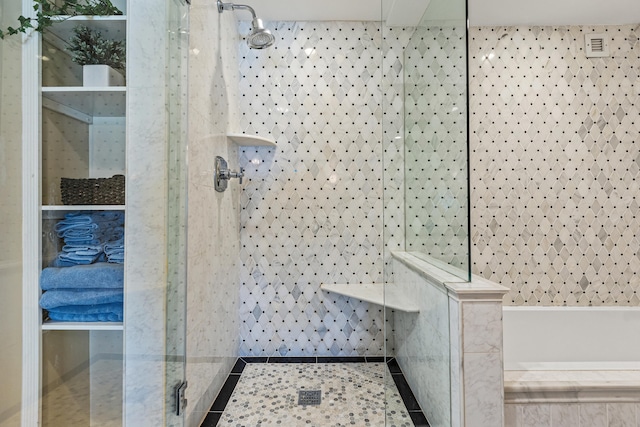 bathroom with tiled shower and tile patterned flooring