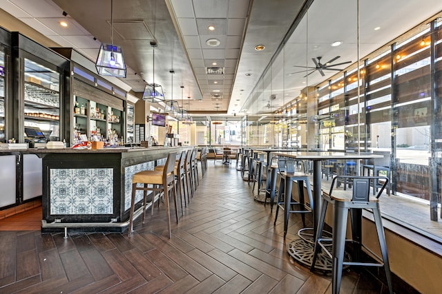 bar with ceiling fan, parquet floors, and decorative light fixtures