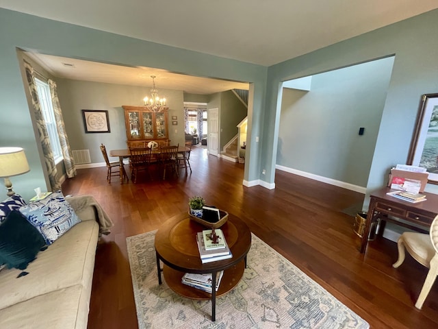 living room with dark wood-type flooring and a chandelier