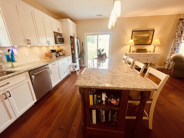 kitchen featuring white cabinetry, a kitchen breakfast bar, hanging light fixtures, and appliances with stainless steel finishes