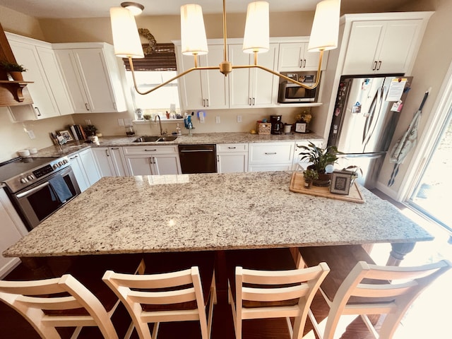 kitchen with decorative light fixtures, a breakfast bar, appliances with stainless steel finishes, and sink