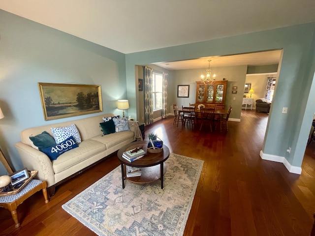 living room with dark wood-type flooring and a notable chandelier