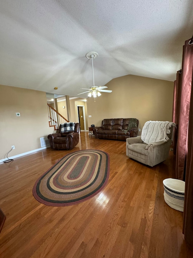 living room with ceiling fan, wood-type flooring, a textured ceiling, and vaulted ceiling