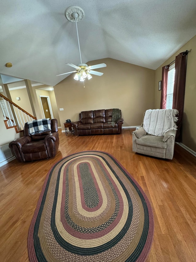 living room with ceiling fan, a textured ceiling, light wood-type flooring, and lofted ceiling