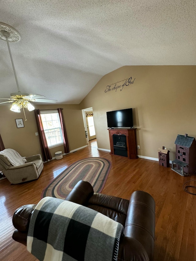 living room featuring ceiling fan, wood-type flooring, a textured ceiling, and lofted ceiling