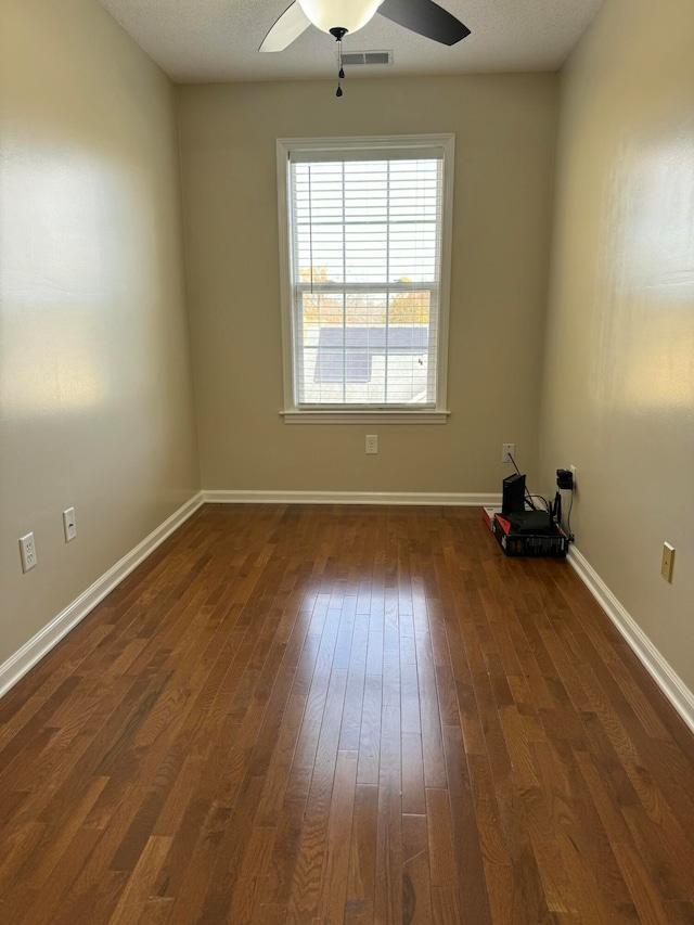 empty room featuring ceiling fan, a textured ceiling, and dark hardwood / wood-style flooring