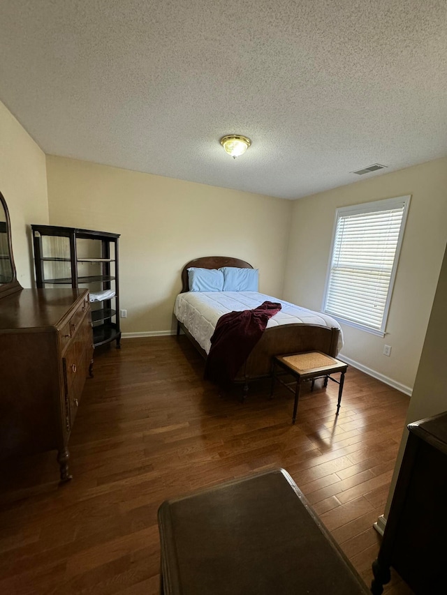 bedroom with a textured ceiling and dark hardwood / wood-style floors