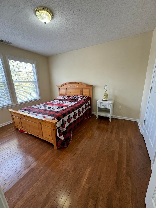 bedroom with dark wood-type flooring and a textured ceiling