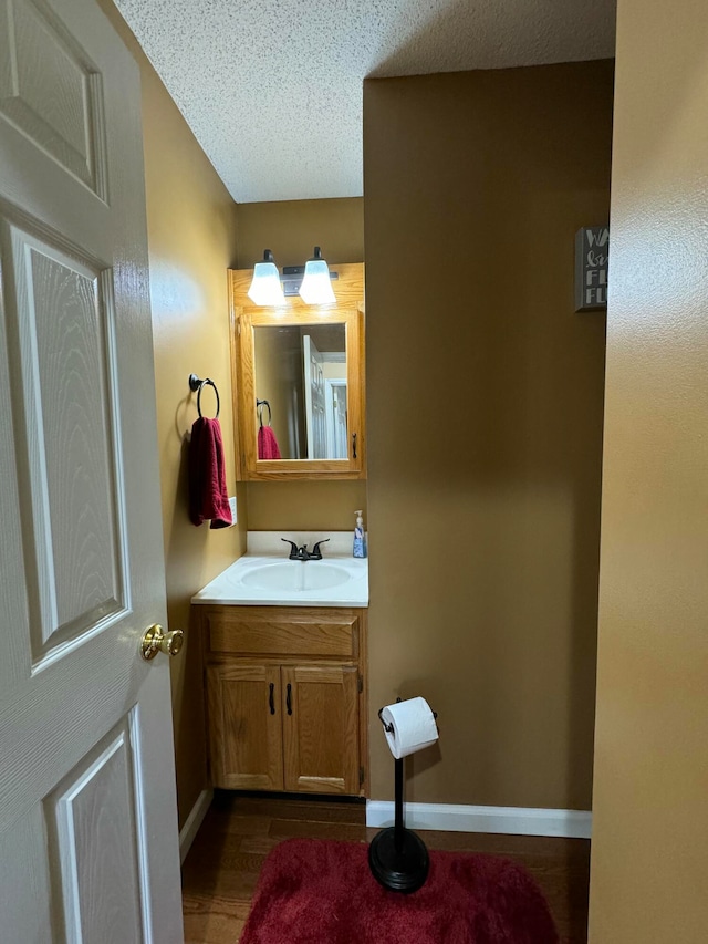 bathroom featuring hardwood / wood-style flooring, vanity, and a textured ceiling