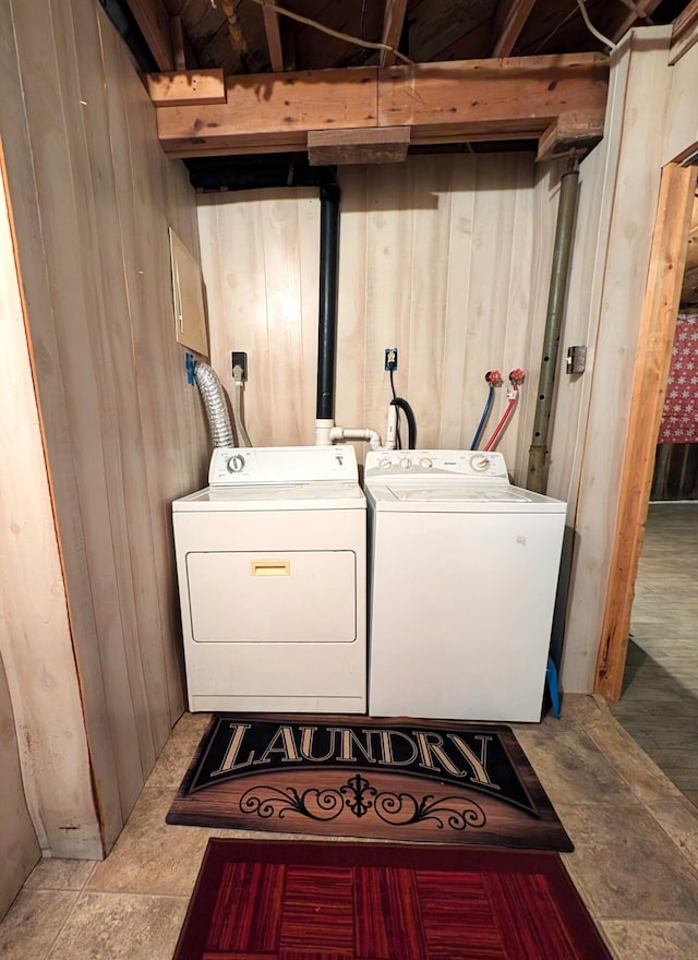 clothes washing area with wooden walls and separate washer and dryer